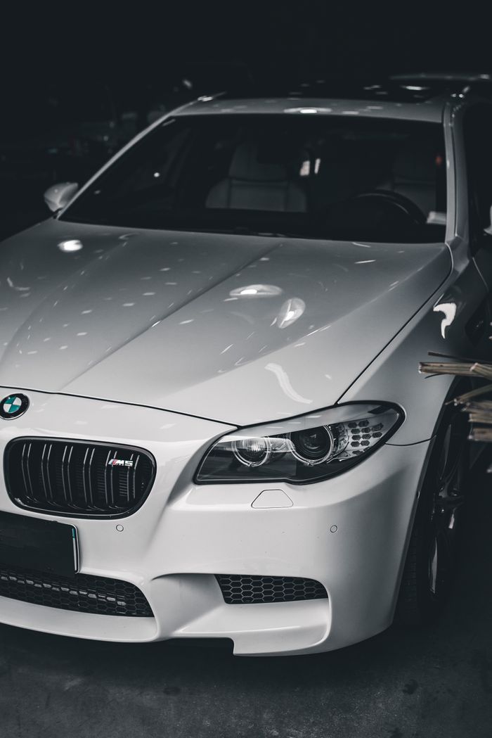 Stylish white luxury car with BMW badge under soft lighting in a dark garage.