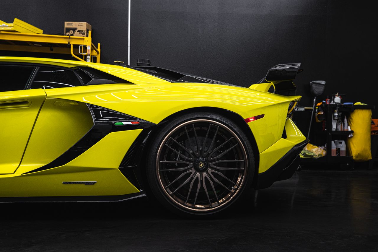 Close-up of a yellow Lamborghini Aventador parked indoors in a garage setting.